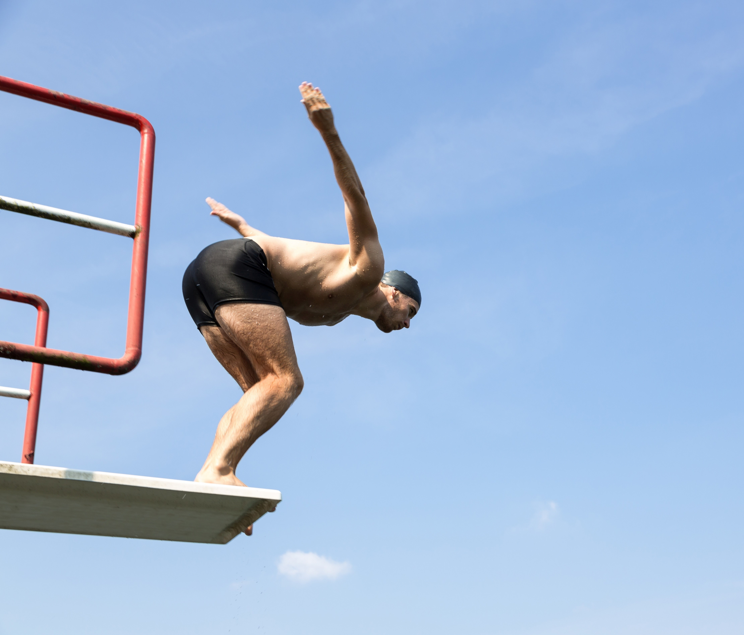 Man jumping off diving board at swimming pool